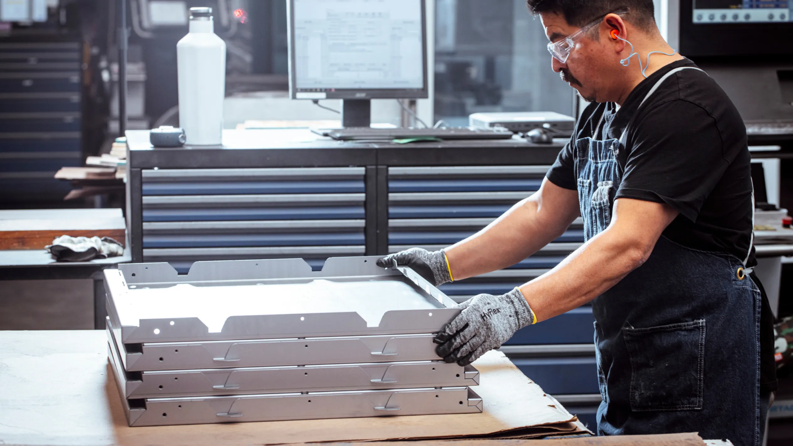 A worker handling components for high quality custom metal cabinets, showcasing the manufacture of high quality built cabinets for tools and gear.