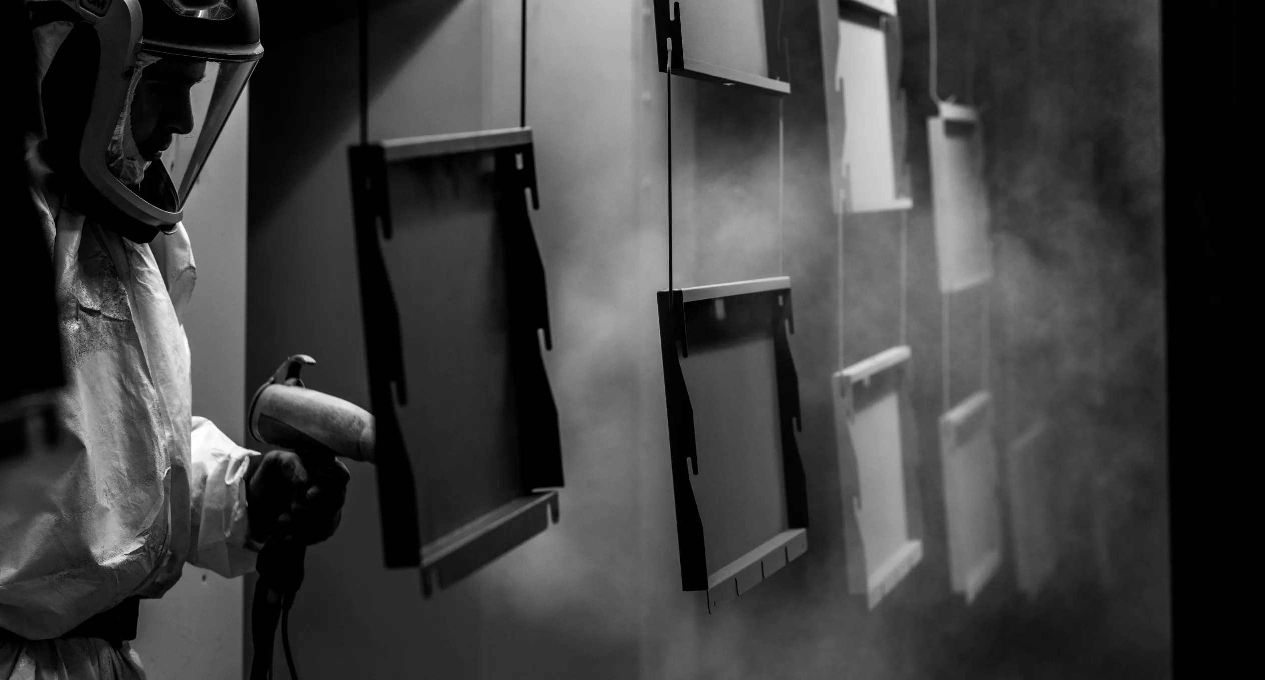 Worker carefully applying a powder coating to a metal cabinet, ensuring a smooth and durable finish for custom cabinetry.